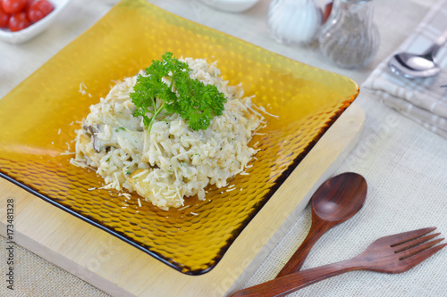 Risotto mushroom (Fried rice Italian style) in glass square plate on wood cutting board. photo