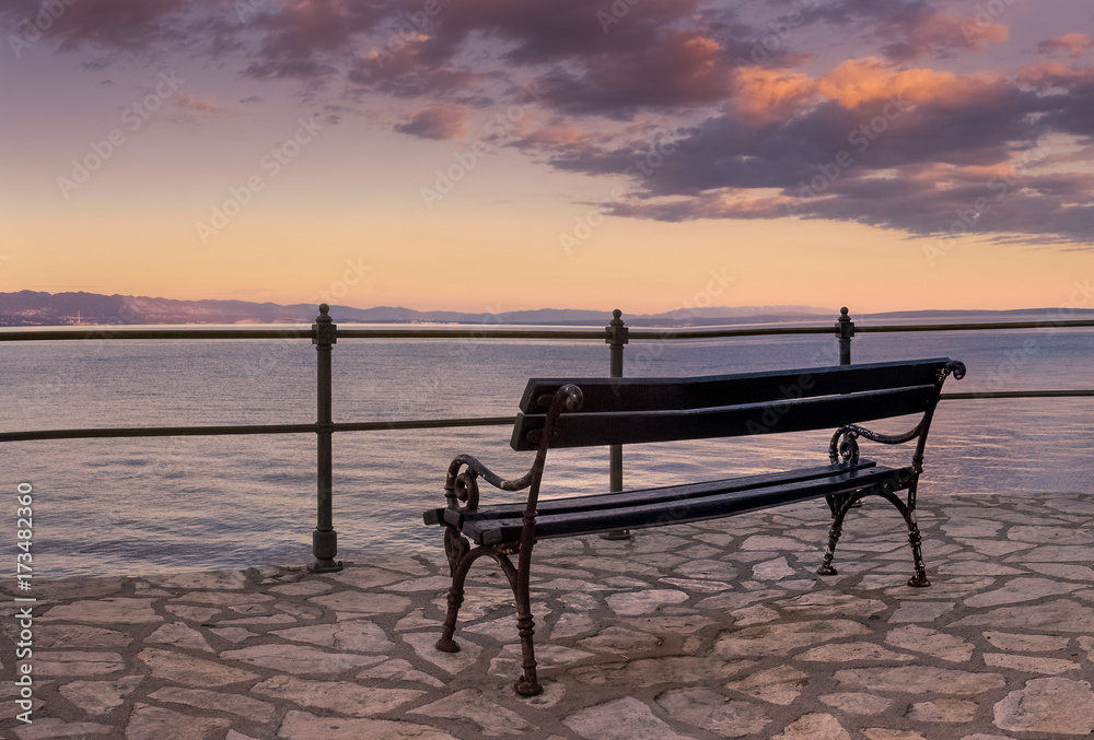 An empty bench by the sea waiting for some tired passer-by