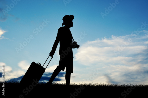 Silhouette of man travel walking with luggage at the sky sunset