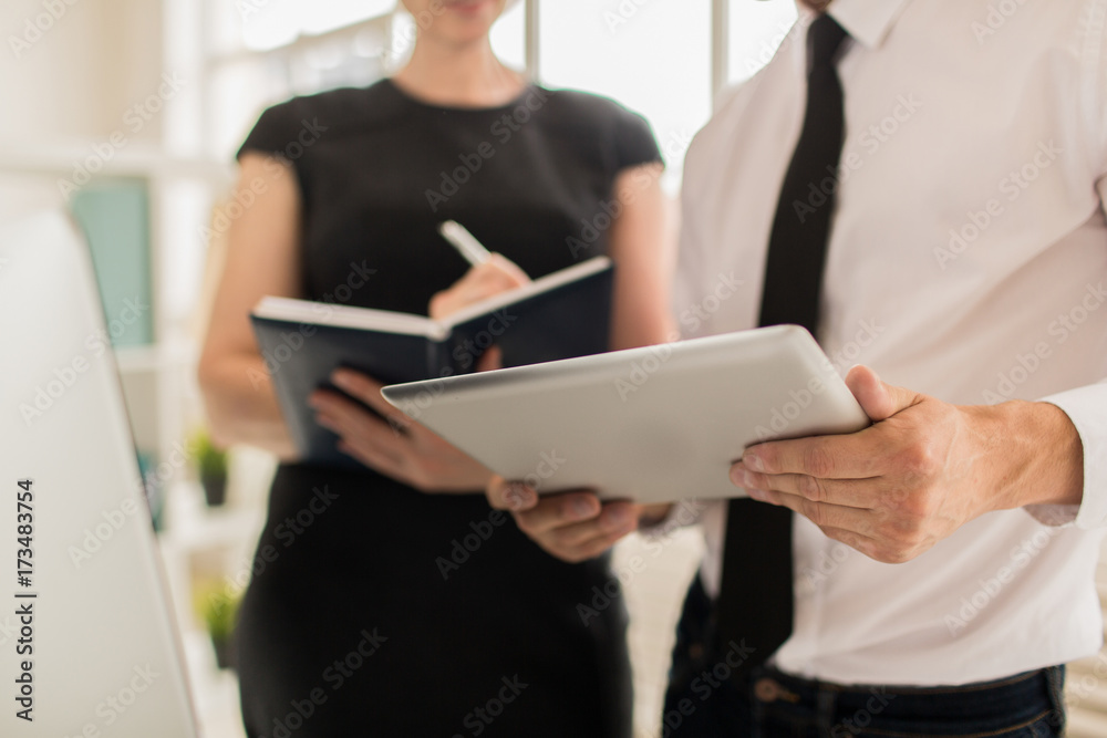 Close-up shot of unrecognizable colleagues analyzing statistic data presented on digital tablet screen while having working meeting at open plan office, blurred background Close-up shot of unrecognizable colleagues analyzing statistic data presented on digital tablet screen while having working meeting at open plan office, blurred background