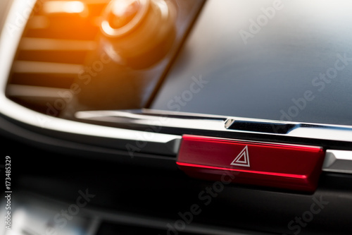 close-up of car dashboard, hazard flasher switch or emergency light button in modern car with sunlight effect, shallow depth of field