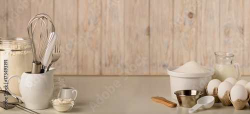 Kitchen utensils and tools for homemade baking on a light wooden background.