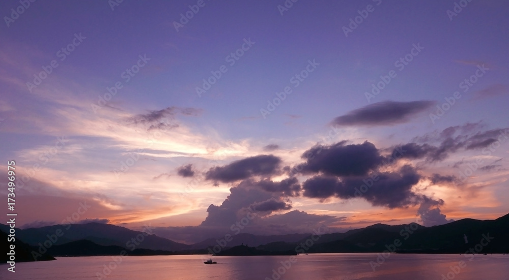 The mountain, dramatic sky with clouds, boat on ocean at sunset