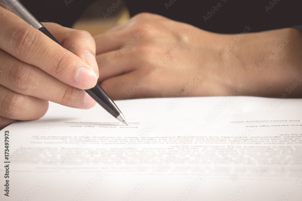 Man is holding pen in hand and writing / signing on contract peper Man is holding pen in hand and writing / signing on contract peper