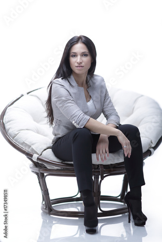 Young woman sitting in a round cozy soft big chair.