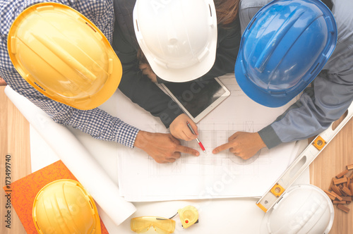 Engineer and foreman wearing safety helmet are meeting at site outdoor and pointing to drawing paper top view