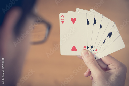 Spielkarten in Männerhänden, Kopf mit Brille