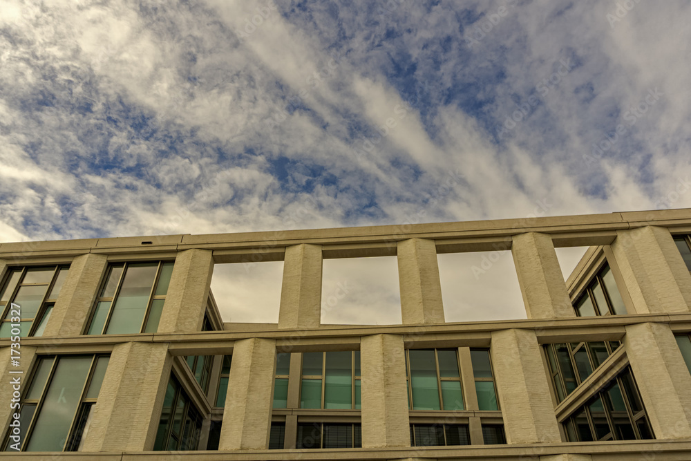 The upper part of a new,modern building below a cloudy sky