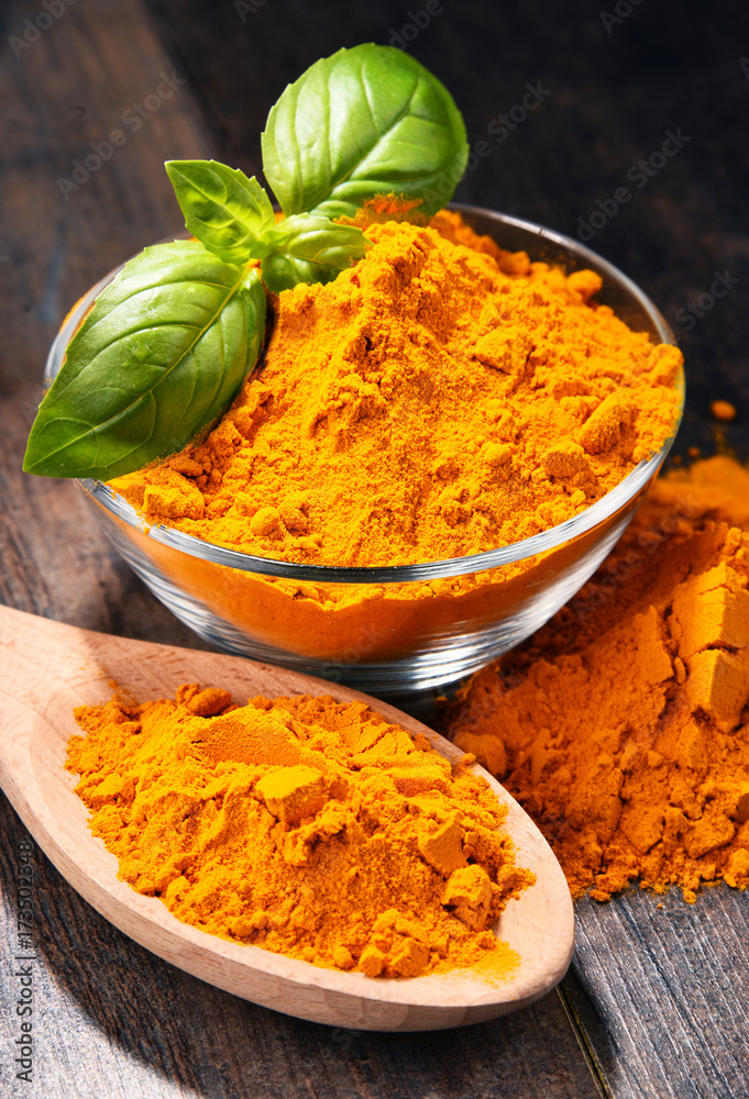 Composition with bowl of turmeric powder on wooden table Composition with bowl of turmeric powder on wooden table