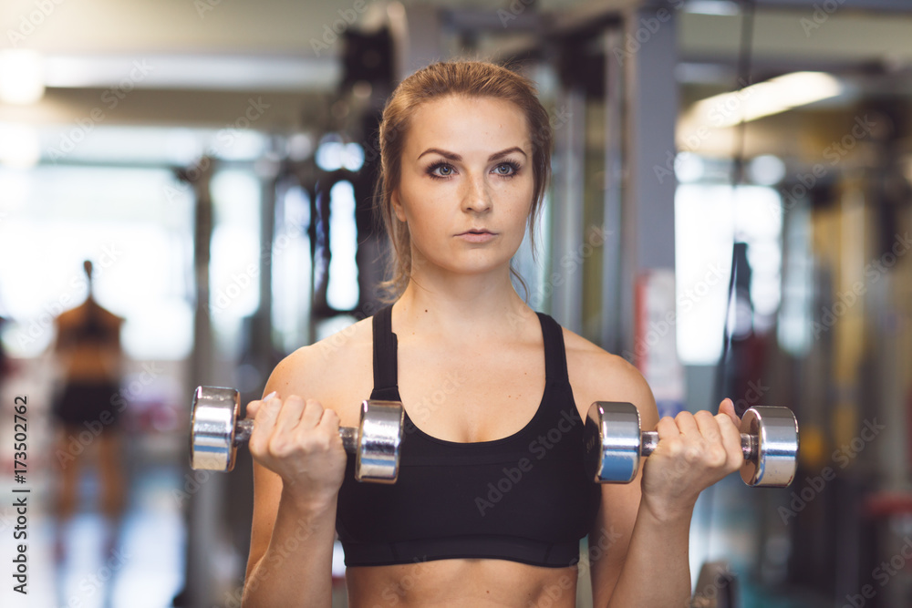 Young fitness girl lifting dumbbells in the gym Young fitness girl lifting dumbbells in the gym