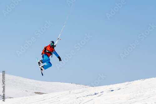 Snowboarder with a kite on fresh snow in the winter in the tundra of Russia against a clear blue sky. Teriberka, Kola Peninsula, Russia. Concept of winter sports snowkite.