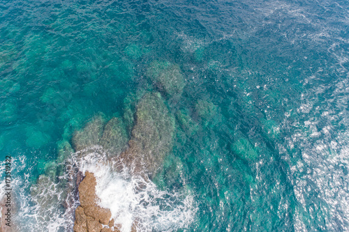 A bird's-eye view of how turquoise waves beat about sea cliffs in Montenegro