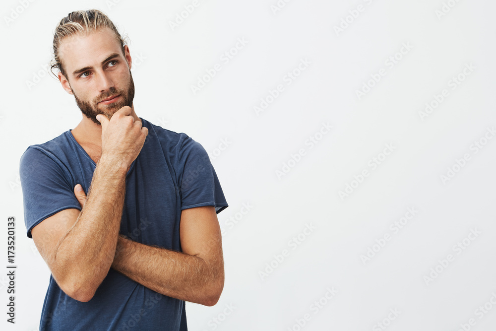 Close up portrait of beautiful bearded man with stylish hairstyle and clothes looking aside and thinking about room design. Close up portrait of beautiful bearded man with stylish hairstyle and clothes looking aside and thinking about room design.