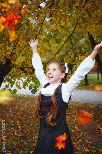 Girl school girl in school uniform, throwing yellow leaves in the air,autumn in the Park.