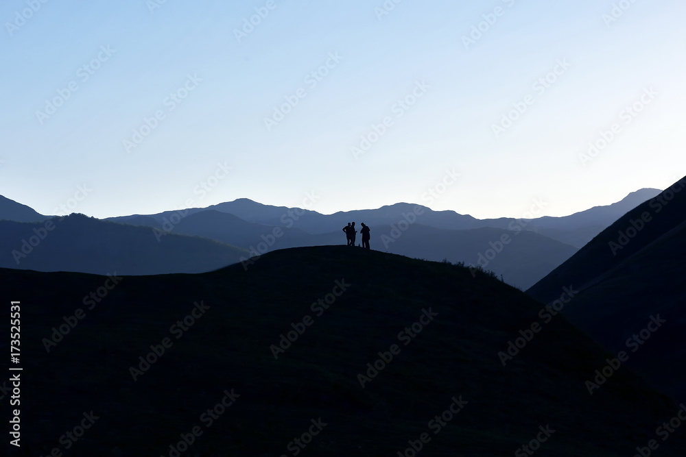 silhouette of people standing on the hillside