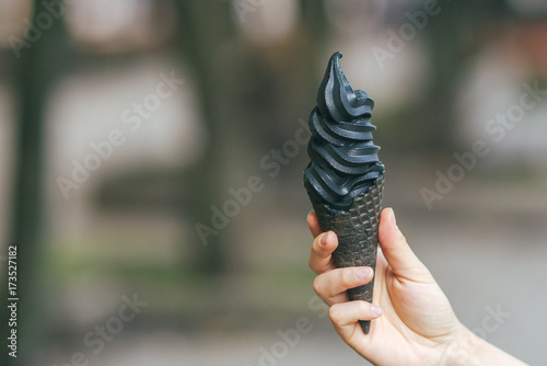 Holding black ice cream, blurred background