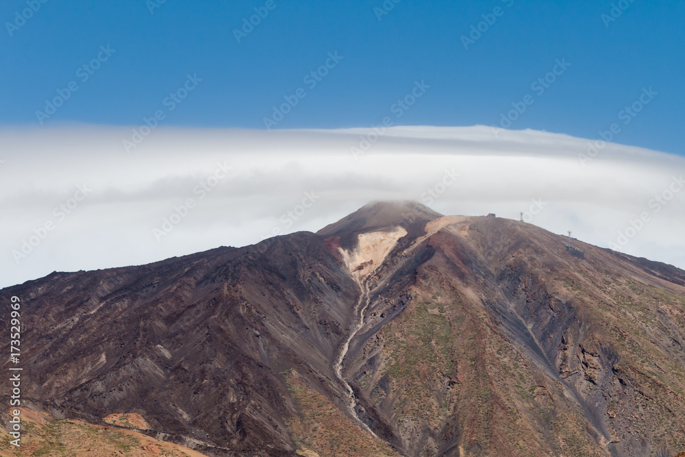 View at Mount Teide Volcano peak covered in clouds and lava formations in Teide National Park in Tenerife