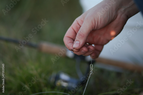 рыбак насаживает червяка на крючок на рыбалке  © polukarovaanna