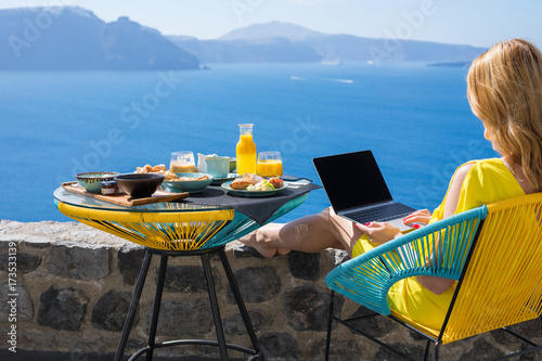 Принти на полотні Woman working with laptop computer while eating breakfast