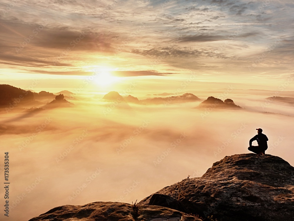Φωτογραφία Tourist sit on peak of sandstone rock and watching into colorful mist and fog in  morning valley