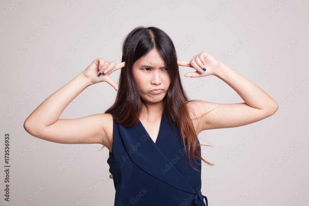 Young Asian woman block both ears with fingers. Young Asian woman block both ears with fingers.