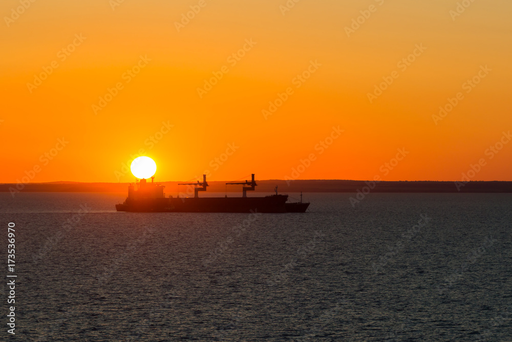 Dry cargo vessel at anchor when it sunset.