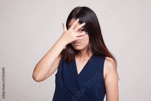 Beautiful young Asian woman peeking through fingers.