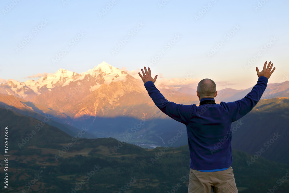 man with and raised hands standing in front of the mountains man with and raised hands standing in front of the mountains