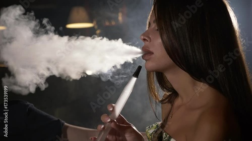 The guy with the girl is sitting on the sofa in the cafe and smoking a hookah photo