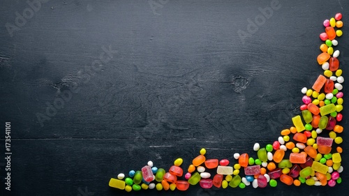 Colored candies, sweets and lollipops. On a black wooden background. Top view. Free space.
