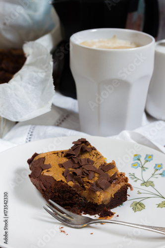 Chocolate brownie with peanut butter. Cup of coffee  floral plate  wooden table.