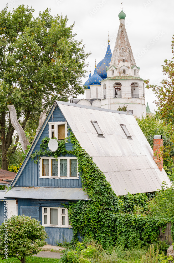 View of a traditional wooden house and the Suzdal Kremlin in the background