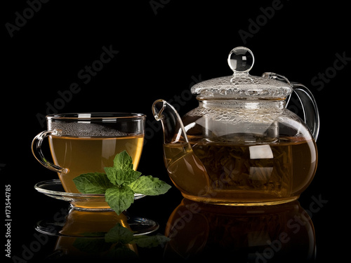 Fresh mint and green tea in a cup and a teapot from glass