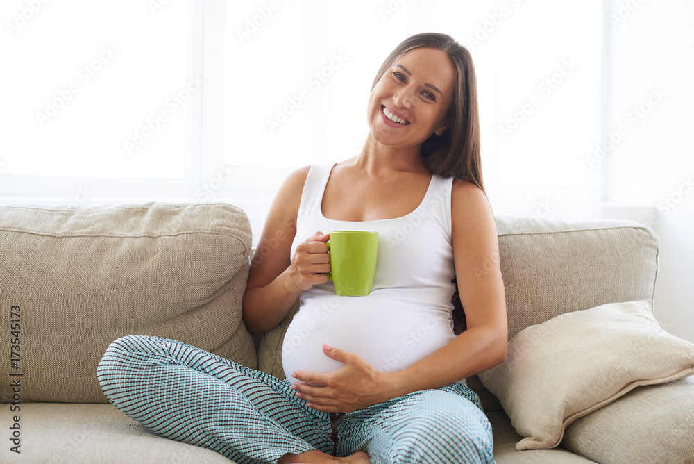 Pregnant woman sitting with cup of tea on sofa Pregnant woman sitting with cup of tea on sofa