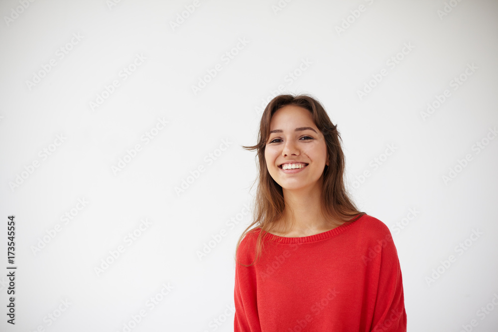 Picture of attractive cheerful young Hispanic lady dressed in oversize red sweater grinning broadly at camera, her eyes expressing joy. Positive friendly looking girl posing isolated in studio Picture of attractive cheerful young Hispanic lady dressed in oversize red sweater grinning broadly at camera, her eyes expressing joy. Positive friendly looking girl posing isolated in studio