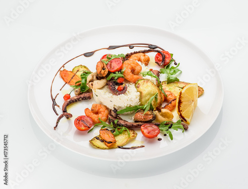 The seafood fried with ricotta on a white plate. Decorated with goji and ruccola.