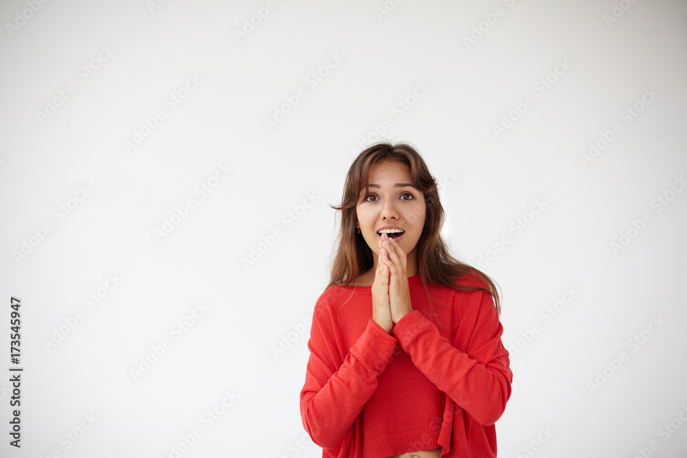 Beautiful young female with loose long hair holding clasped hands in front of her while waiting for something with excited impatient look. Teenage girl looking amazed after she saw dress of her dreams Beautiful young female with loose long hair holding clasped hands in front of her while waiting for something with excited impatient look. Teenage girl looking amazed after she saw dress of her dreams