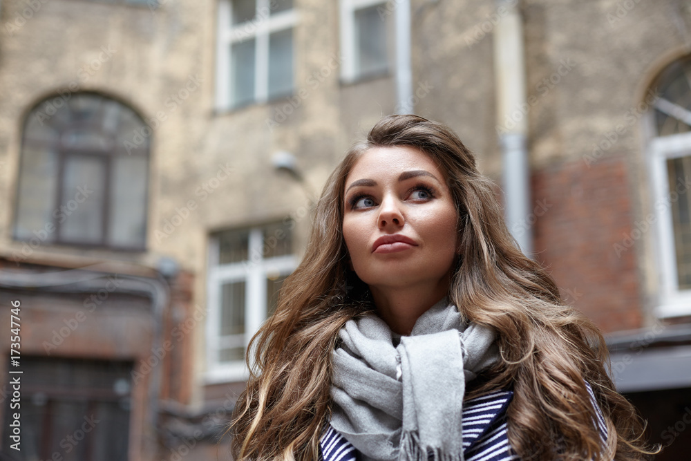 Low angle outdoor autumn portrait of confident gorgeous young Caucasian woman employee dressed in stylish elegant clothes going to work in the morning, with old apartment building in background