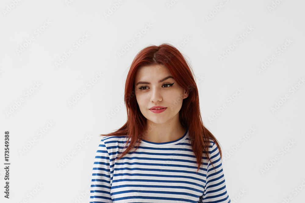 Beauty and skincare concept. Studio shot of charming young European woman in striped t-shirt posing in studio, looking ahead of her with pensive deep-in-thoughts expression on her pretty face Beauty and skincare concept. Studio shot of charming young European woman in striped t-shirt posing in studio, looking ahead of her with pensive deep-in-thoughts expression on her pretty face