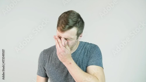 Young man sneezing on a white background, slow motion photo