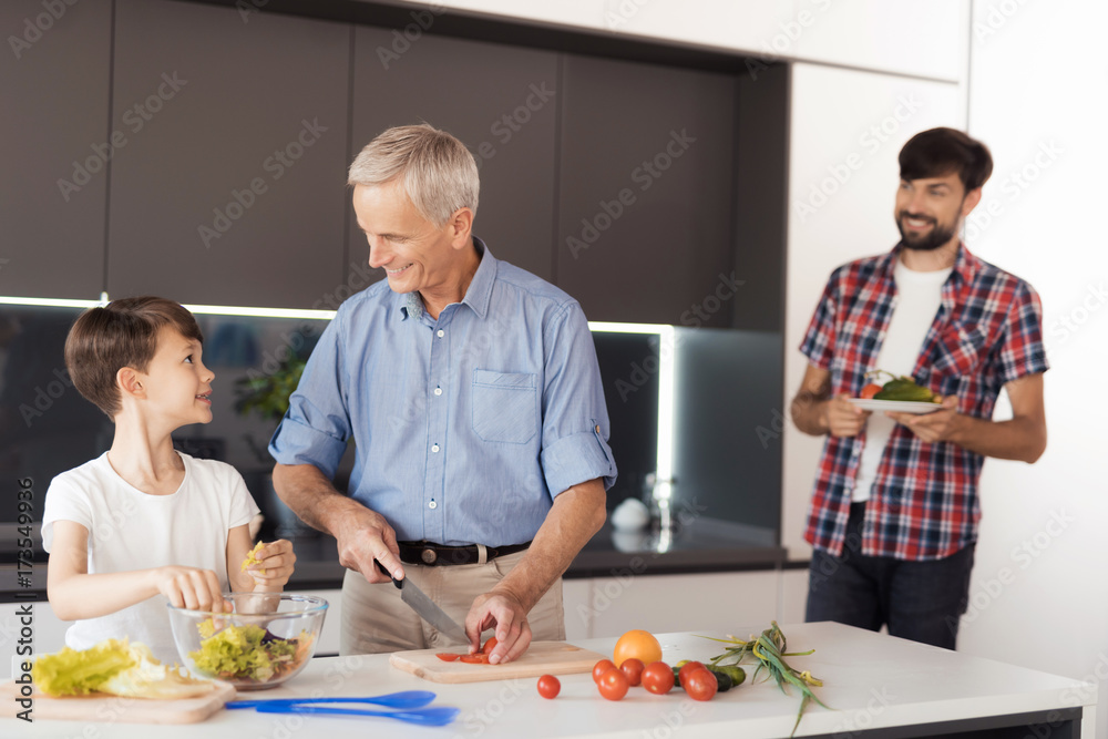 The old man and the boy are preparing a salad. The boy's father brought them more vegetables The old man and the boy are preparing a salad. The boy's father brought them more vegetables