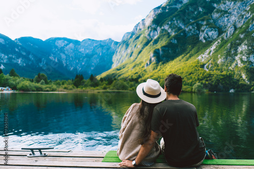 Rear view of couple sitting on pier by lake