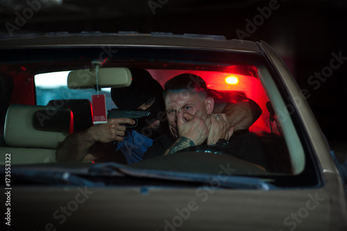 Car thief threatening driver with the gun.
