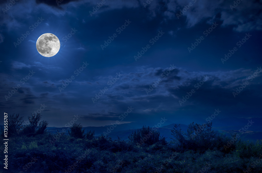 Mountain Road through the forest on a full moon night. Scenic night landscape of dark blue sky with moon