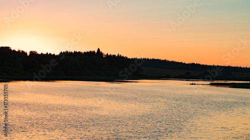 Beautiful Summer Landscape: Wide River Under Saturated Yellow Orange Sky With Sunset Behind Trees.