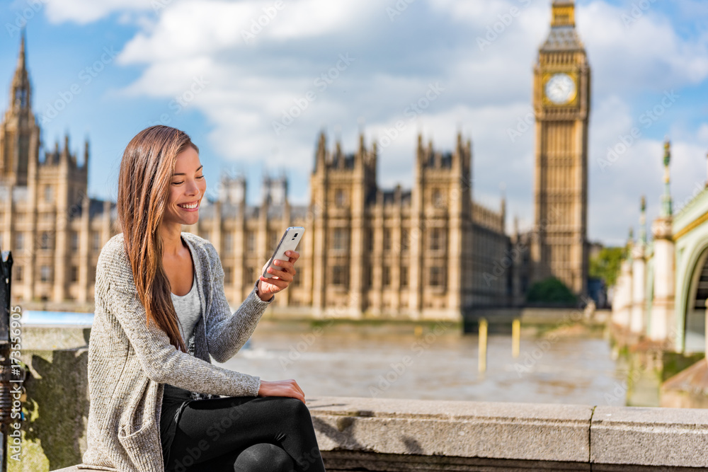 Naklejka premium Miejski styl życia ludzi miejskich Londynu młoda kobieta Azji za pomocą aplikacji SMS-y na telefon komórkowy sms na social media. Szczęśliwy student uniwersytetu dziewczyny mienia telefon komórkowy przy Westminister mostem, Big Ben tło.