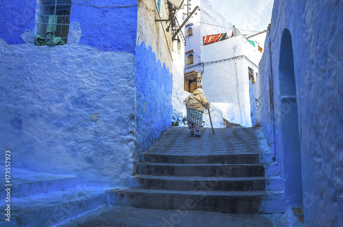 Woman in typical moroccan clothing, walking down a street in Chefchaouen city. © Mariana Ianovska