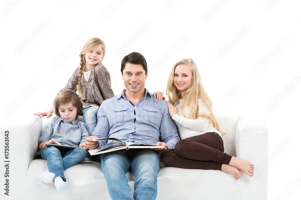 Happy family mother, father, daughter and son at home on sofa isolated on white. Happy family mother, father, daughter and son at home on sofa isolated on white.