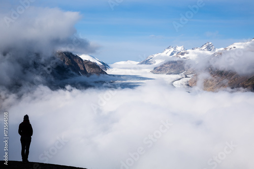 Silhouette of young woman standing over the Salmon Glacier on a foggy morning in British Columbia, Canada.