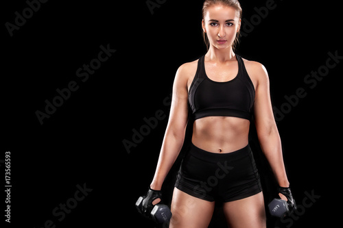 Sporty beautiful woman with dumbbell exercising at black background to stay fit. Crossfit workout motivation.